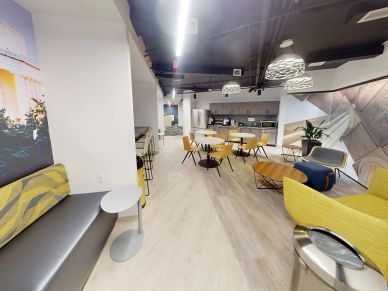 Modern office lounge with yellow chairs and wooden tables.