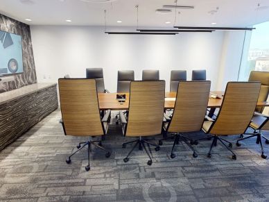 Modern conference room with wooden chairs and table.