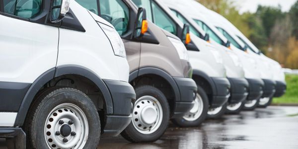 A row of parked delivery vans in a parking lot.
