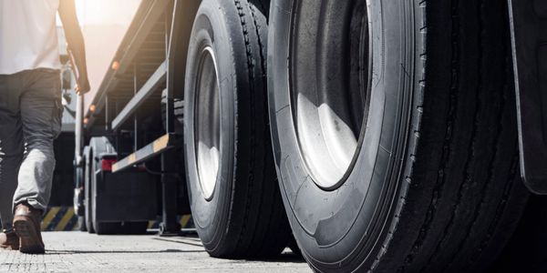 Close-up of large truck tires with a person walking nearby.