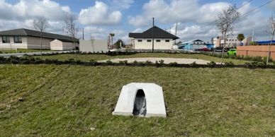Small concrete structure on grassy slope in suburban area.