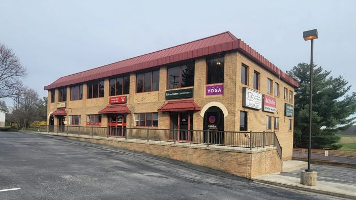 Two-story brick office building with various business signs and a red roof.