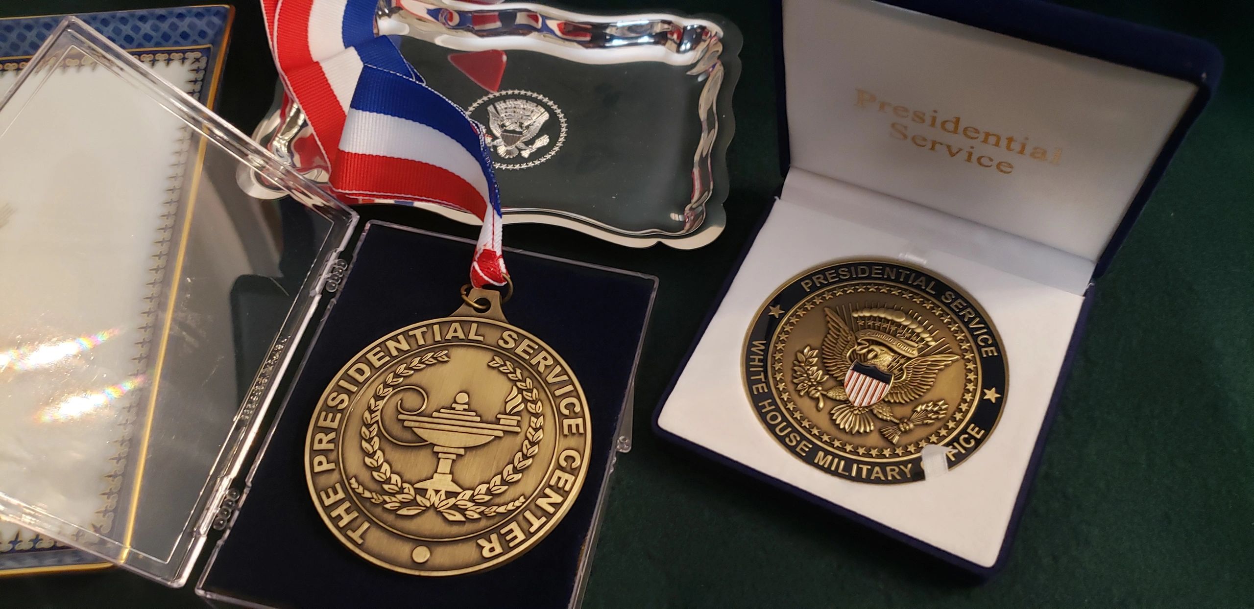 A picture of a gold medal and a gold-colored coin from the US Presidential Service Center.