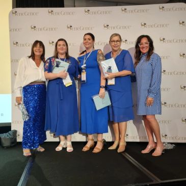 Five women in blue outfits posing at an event.