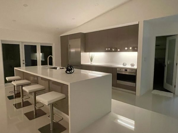 Modern kitchen with a large white island and bar stools under warm lighting.
