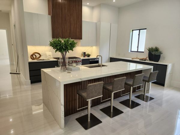 Modern kitchen with marble island and four bar stools.