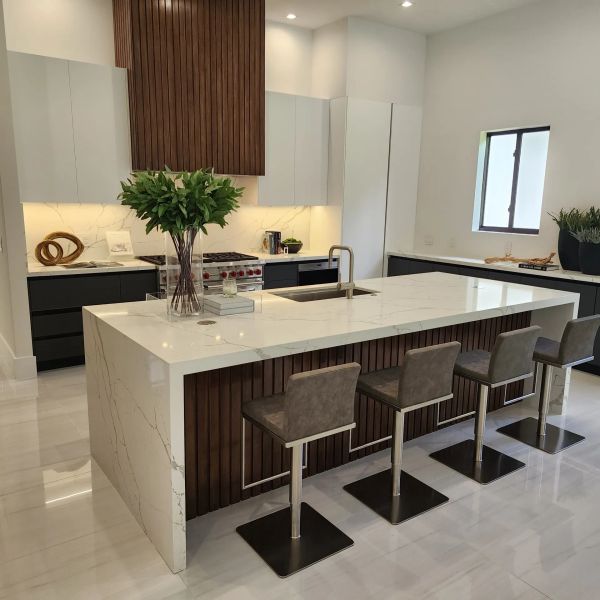 Modern kitchen with marble island and four bar stools.