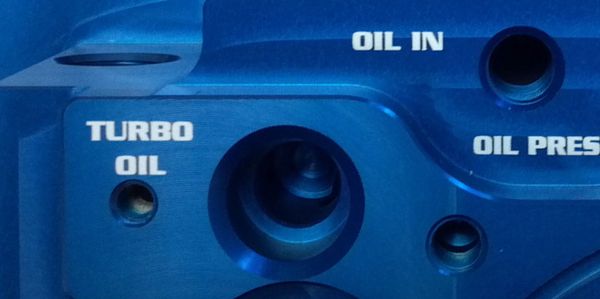 Blue anodized part with engraving on multiple surfaces. 