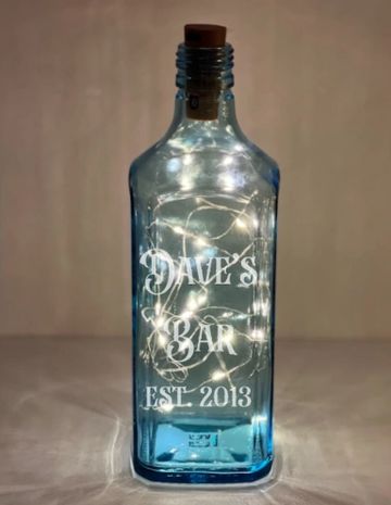 Blue glass bottle with fairy lights and 'Dave's Bar Est. 2013' engraving.