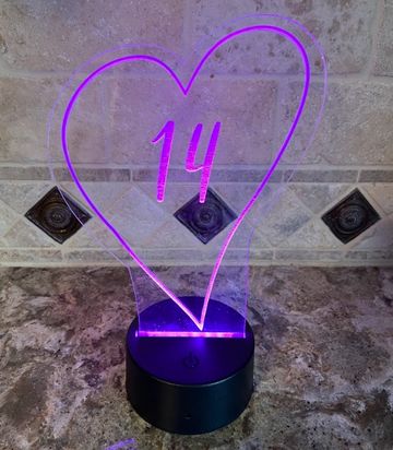 A purple neon heart with the number 14 inside on a black base.