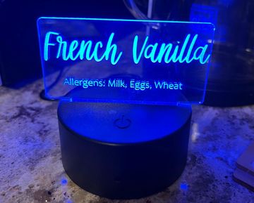Blue-lit sign displaying "French Vanilla" with allergen info.