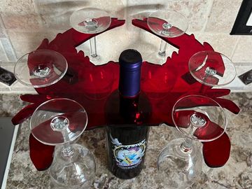 Ruby red crab shaped wine glass caddy shown sitting on top of a wine bottle and holding six upside d