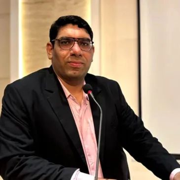 Man in glasses speaking at a podium with a microphone.