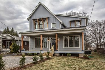 Gray two-story house with a front porch and wooden accents.