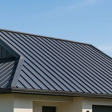 Modern house with a sleek dark metal roof under a clear blue sky.