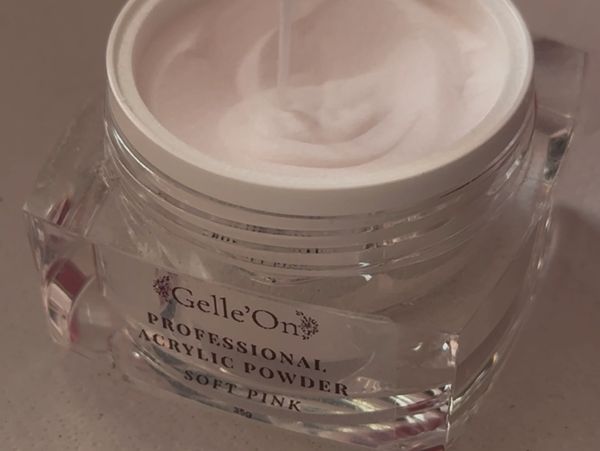 Open jar of soft pink professional acrylic powder with a scoop inside.
