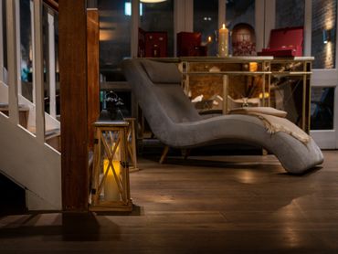 Cozy lounge area with a lit lantern and a comfortable chaise lounge.