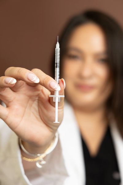 A woman holding a syringe with a blurred background.