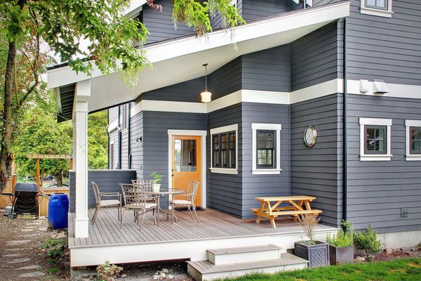Modern gray house with a cozy wooden porch and outdoor seating.