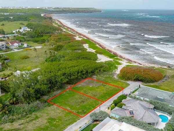 Oceanfront land marked by red lines near a beach with houses.