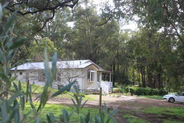 Cottage set on a rural property with surrounding trees.