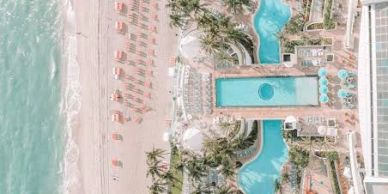 Aerial view of a beach resort with pool and lounge chairs.