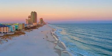 Sunset view of a beach with buildings and waves.