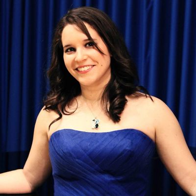 Mujer sonriendo con vestido azul y fondo azul.