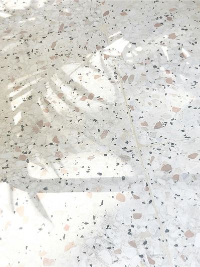 Top-view-of-terrazzo-tile-with-dapples-shadow-of-a-palm-leaf