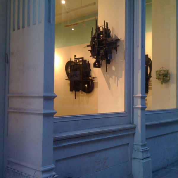 Abstract black metal sculptures displayed in a well-lit gallery window.