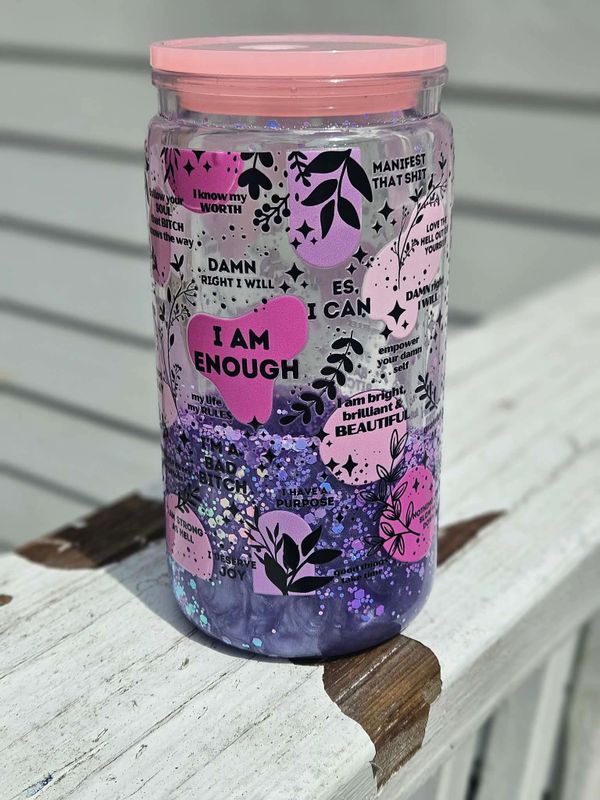 A pink-lidded jar with empowering affirmations and purple glitter inside.