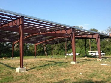 Steel frame construction in progress on grassy land.