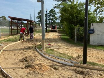 Workers preparing a curved concrete pathway in a park area.
