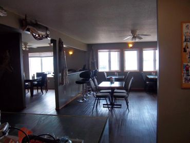 Cozy dining area with tables, chairs, and rustic decor including mounted fish and fur.