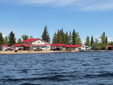 Lakeside buildings with red roofs under a clear blue sky.
