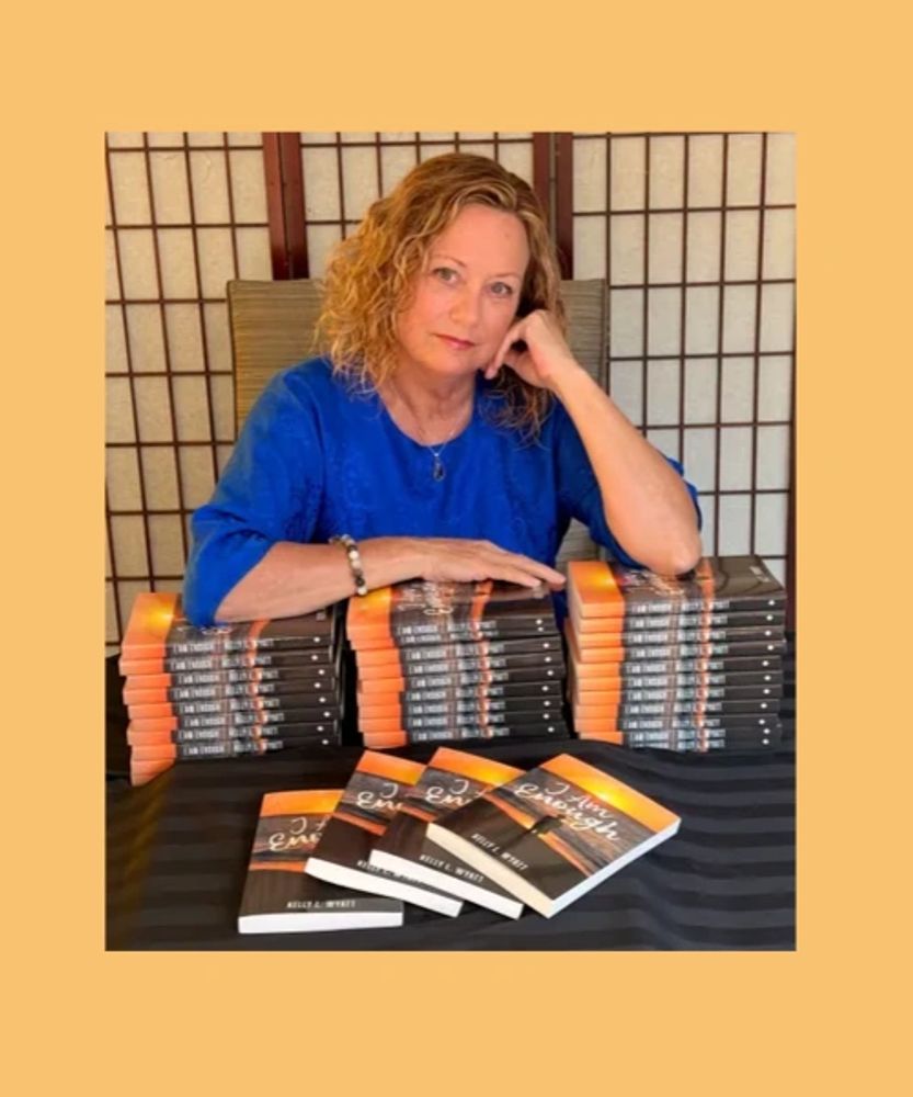 Woman in blue with stacks of books on a table.