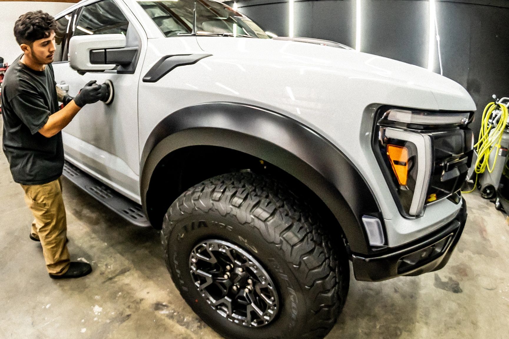 Man polishing the side of a white truck indoors.