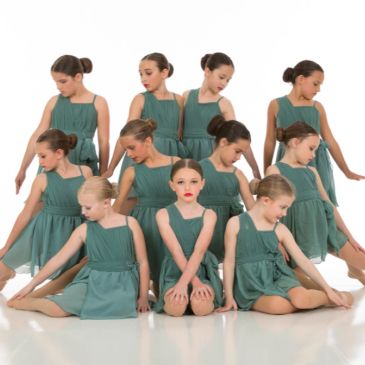 Group of young girls in green dresses posing.