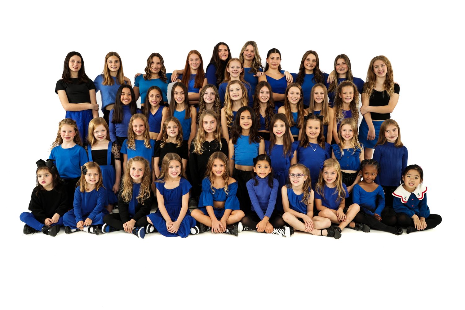 A large group of dancers dressed in royal blue and black, all smiling at the camera.