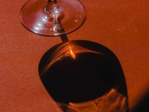 Shadow of a glass with orange light reflections on a textured surface.