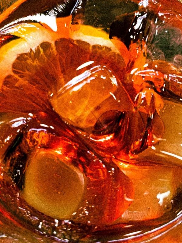Close-up of a drink with ice and an orange slice.