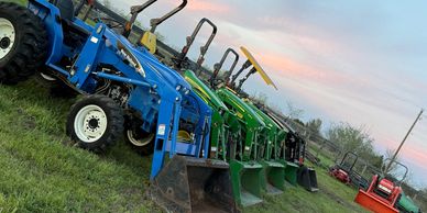 A lineup of colorful tractors on grassy land under a serene evening sky.