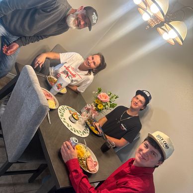 Four people happily gathered around a dining table sharing a meal.