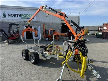 A compact forestry trailer with an orange hydraulic grapple crane outside a North Forest Power Equipment building.