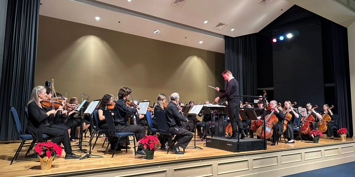 Orchestra performing on stage with conductor.