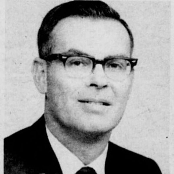 Black and white portrait of a man wearing glasses and a suit.