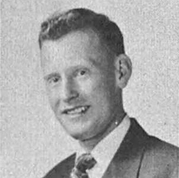 Black and white portrait of a smiling man in a suit and tie.
