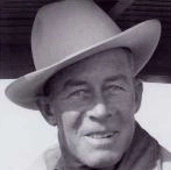 Black and white photo of a man wearing a hat and smiling.
