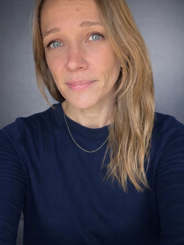 Woman with blue eyes and blonde hair wearing a navy blue shirt.