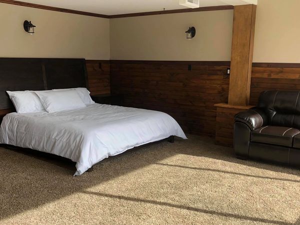 Minimalist bedroom with white bed and leather chair.